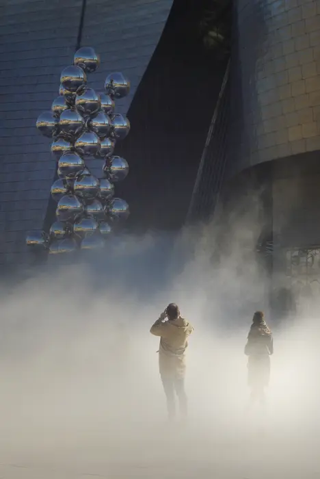 Le musée Guggenheim de Bilbao dans la brume artificielle. Deux adultes dans la brume.